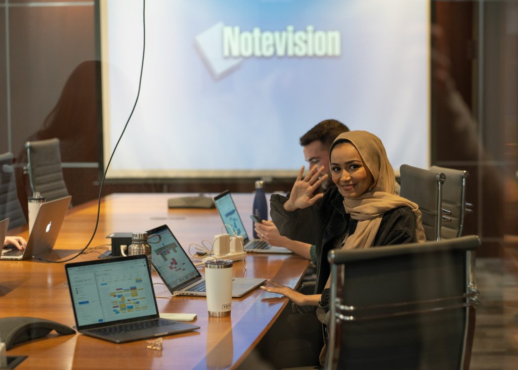 A man and a woman sitting with laptops in a conference room 