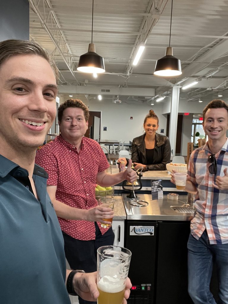 Four employees smiling drinking a beer in the kitchen