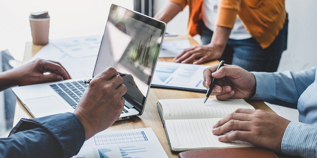 group of people working together on computers and notepads