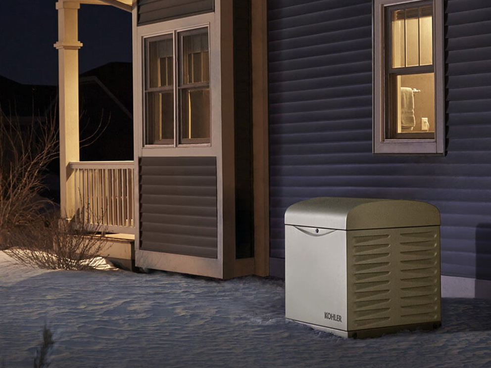 Image of house in the snow with Kohler generator and the lights on