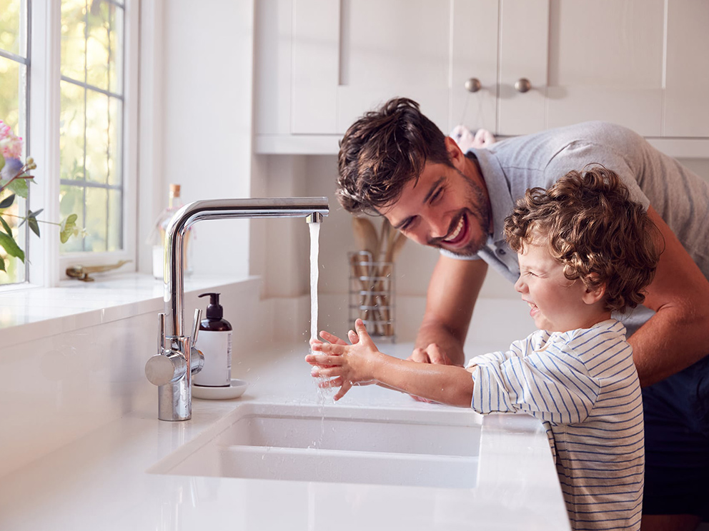 Lifestyle photo of dad and son washing hands in the kitchen